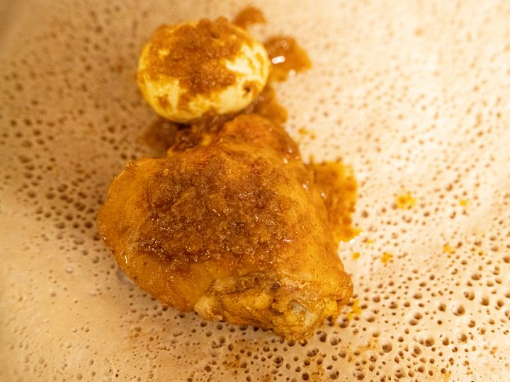 Doro wat chicken with hard-boiled egg served on a round of injera