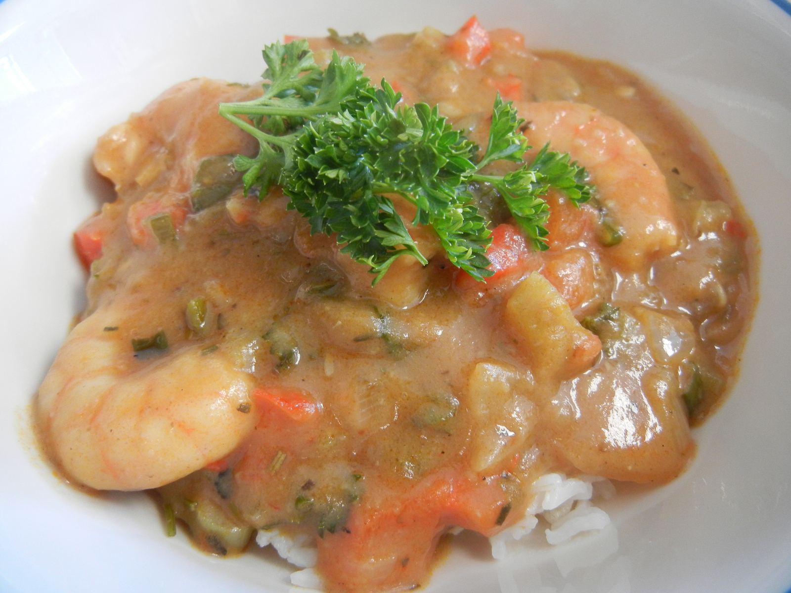 A bowl of seafood gumbo with shrimp and parsley over rice