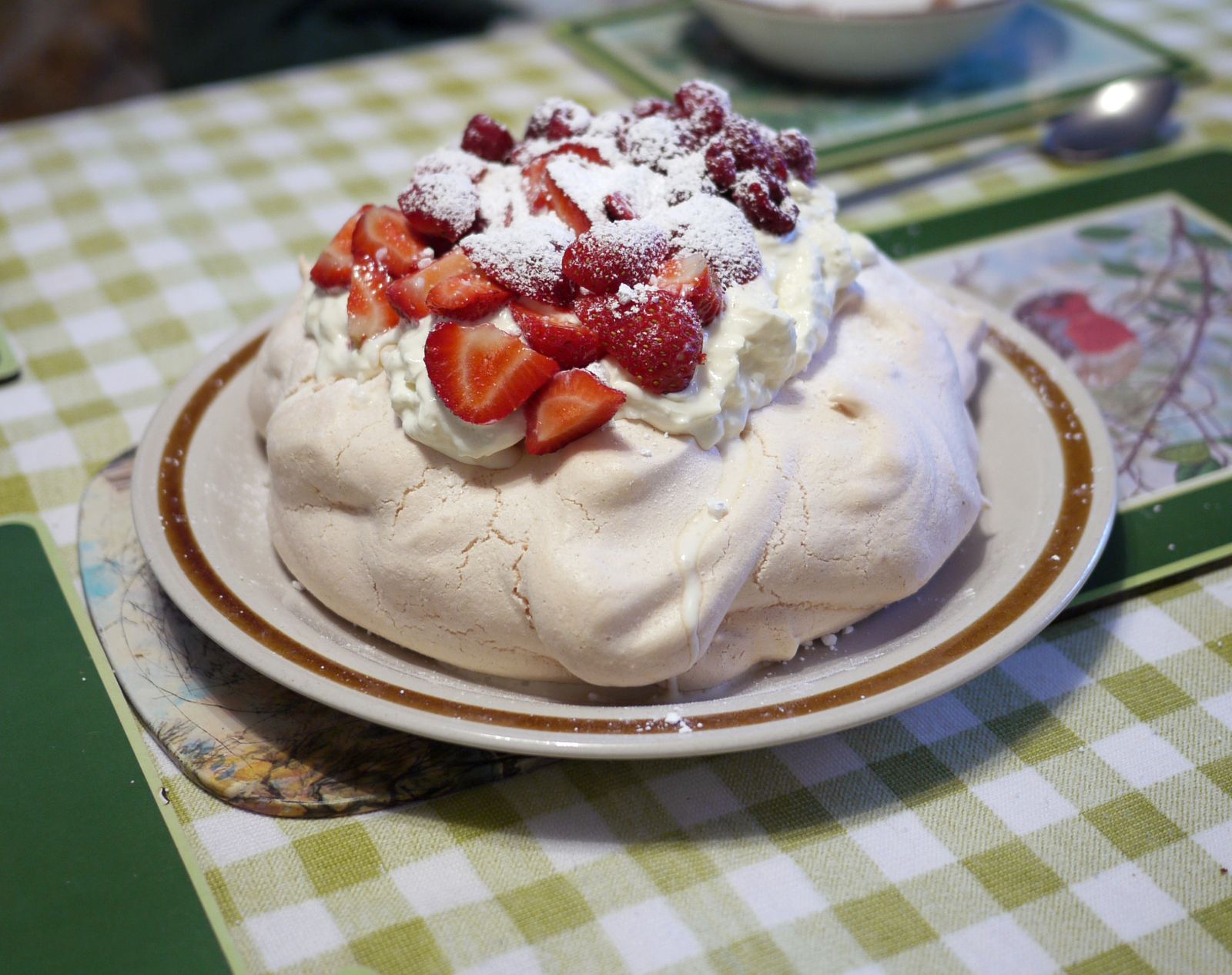 A pavlova topped with whipped cream, strawberries and raspberries
