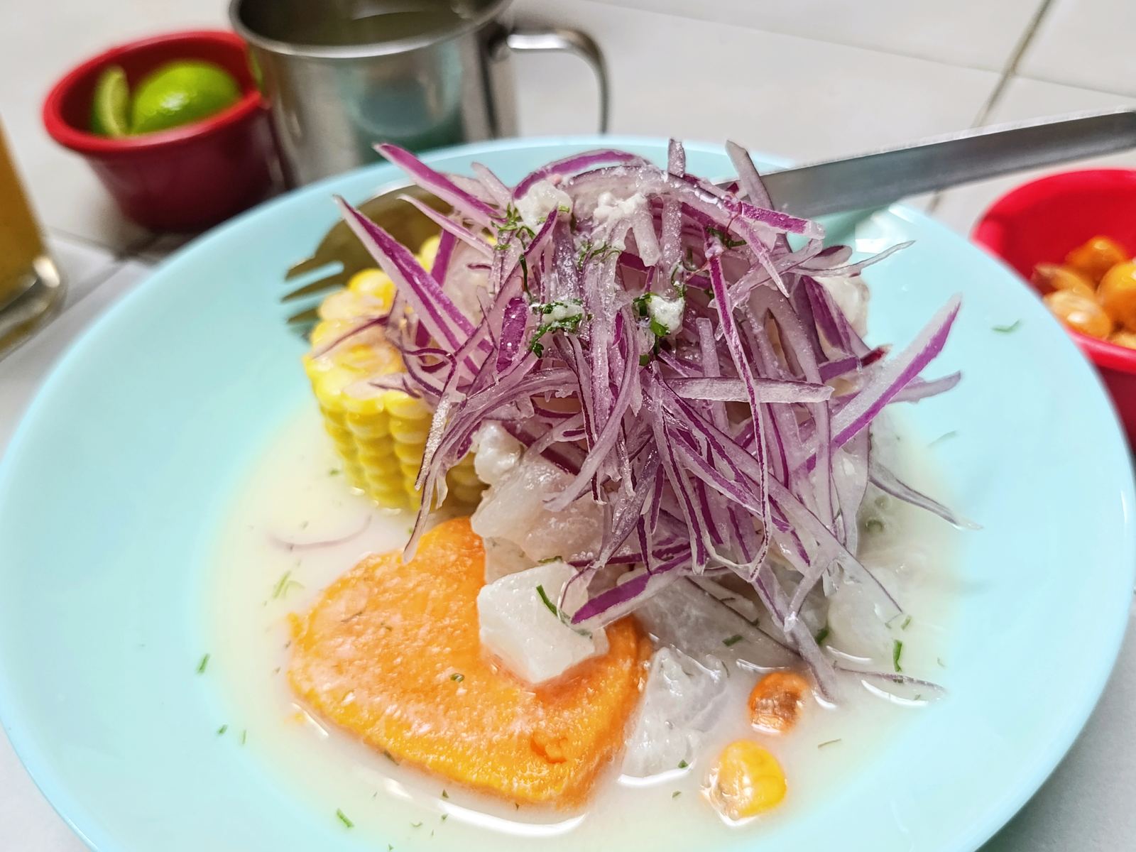 Peruvian ceviche topped with red onion, served with sweet potato and corn